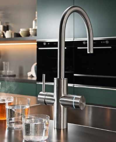 A Franke stainless steel kitchen mixer tap on a worktop, with glasses of water beside it