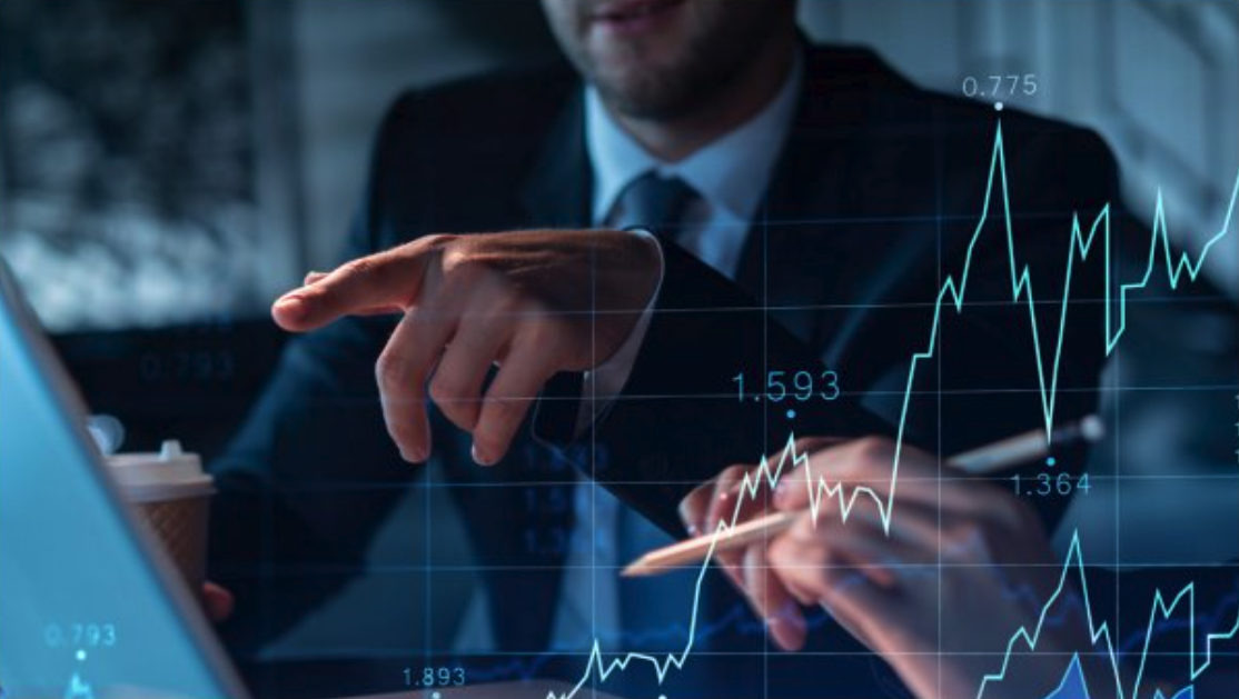 Two people in business attire reviewing financial charts overlaid on a laptop screen